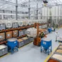 Large warehouse storing food ingredients in bulk containers, with workers and a forklift organizing materials.